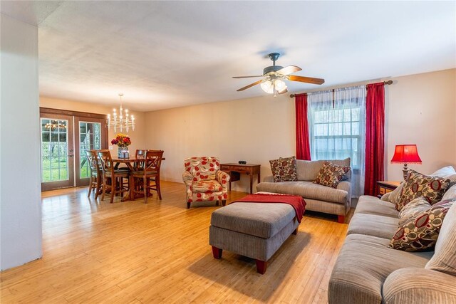 living area featuring ceiling fan with notable chandelier and light wood-type flooring