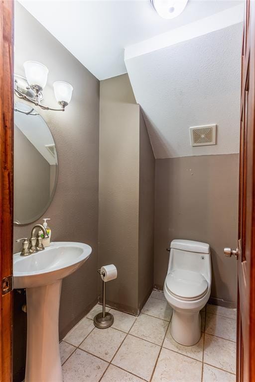 bathroom with tile patterned flooring, vaulted ceiling, toilet, and visible vents