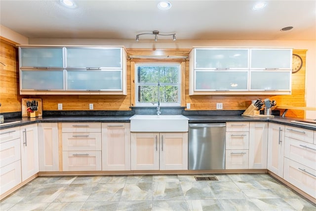 kitchen with a sink, dark countertops, and stainless steel dishwasher