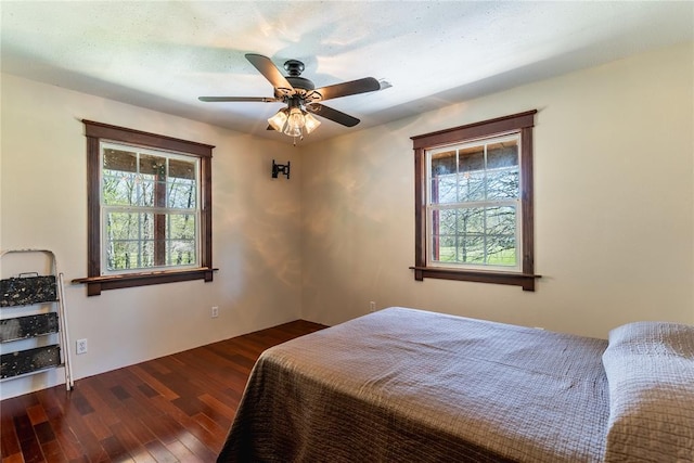 bedroom with a ceiling fan, wood finished floors, and multiple windows