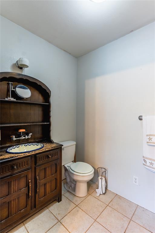 half bath with toilet, tile patterned floors, and vanity