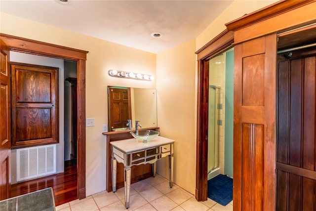 full bathroom with visible vents, a sink, a shower with shower door, and tile patterned floors