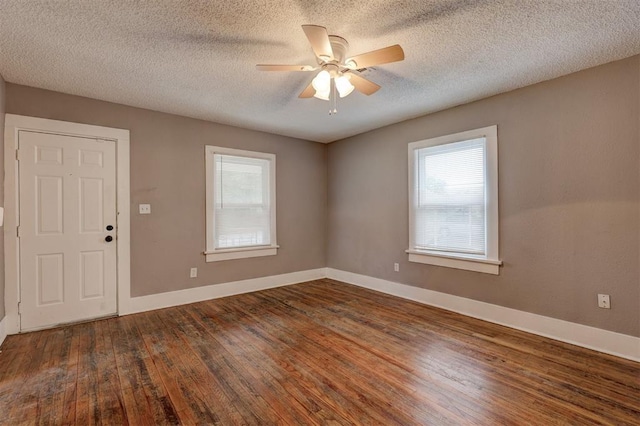 spare room with a healthy amount of sunlight, baseboards, wood-type flooring, and a ceiling fan