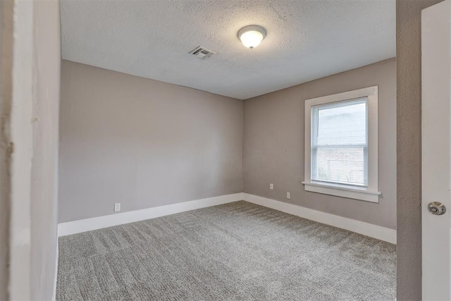 carpeted spare room featuring visible vents, a textured ceiling, and baseboards