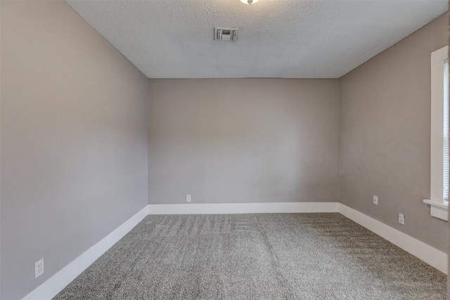 carpeted spare room with baseboards, a textured ceiling, and visible vents