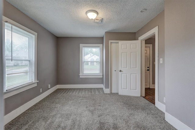 unfurnished bedroom with carpet floors, baseboards, a closet, and a textured ceiling