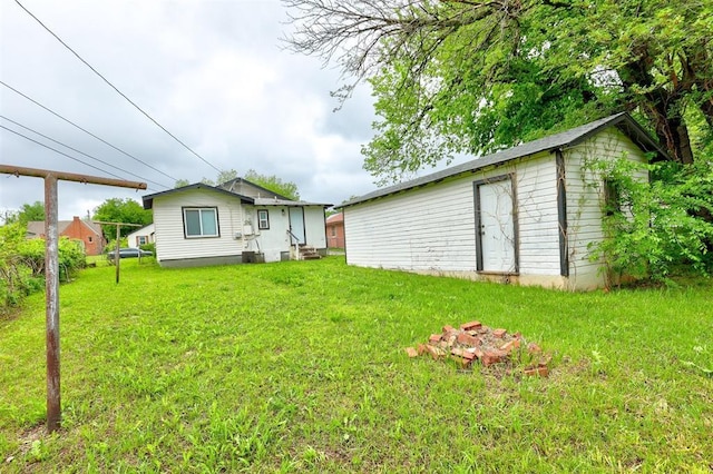 rear view of house featuring an outbuilding, cooling unit, a yard, and entry steps