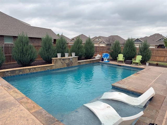 view of swimming pool featuring a fenced backyard, a residential view, a fenced in pool, and a patio area