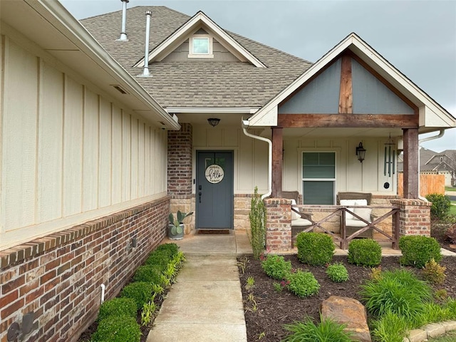 property entrance featuring covered porch, board and batten siding, and roof with shingles