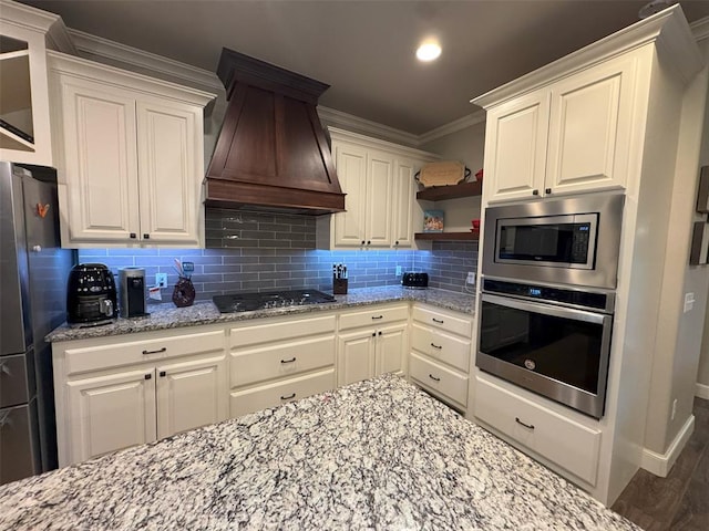 kitchen featuring light stone countertops, custom range hood, backsplash, ornamental molding, and appliances with stainless steel finishes