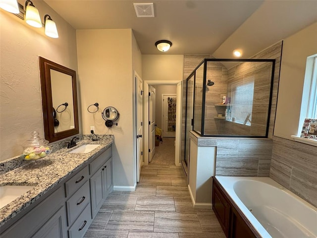 bathroom with a garden tub, a sink, visible vents, and a shower stall