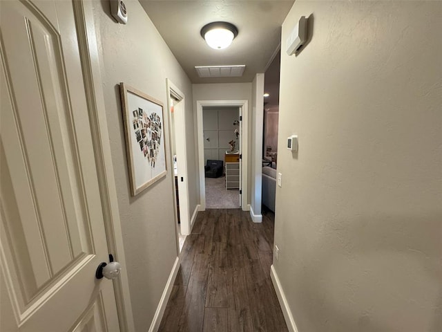 hall featuring visible vents, dark wood-style flooring, and baseboards