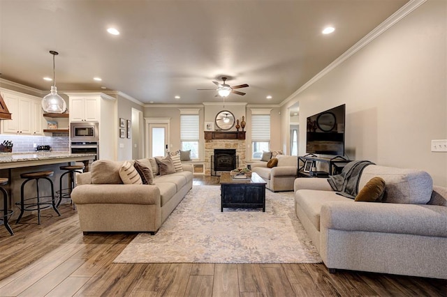 2201 Creek Side Cir, Moore, OK 73160 - living area with wood finished floors, a ceiling fan, recessed lighting, a stone fireplace, and crown molding
