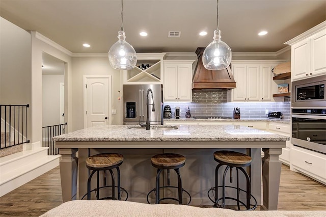 2201 Creek Side Cir, Moore, OK 73160 - kitchen with stainless steel appliances, open shelves, light wood-type flooring, white cabinetry, and ornamental molding