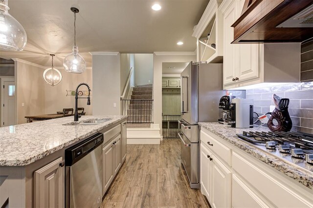 2201 Creek Side Cir, Moore, OK 73160 - kitchen with stainless steel appliances, custom exhaust hood, a sink, ornamental molding, and light wood-style floors