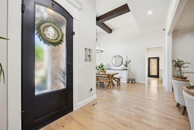 entrance foyer with visible vents, beam ceiling, baseboards, light wood-type flooring, and arched walkways