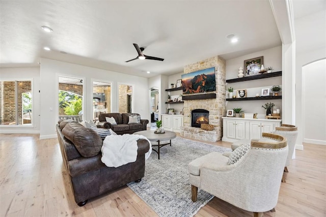 living area featuring light wood-style floors, baseboards, and a fireplace