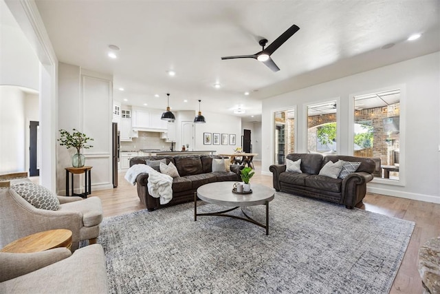 living room with recessed lighting, a ceiling fan, light wood-style flooring, and baseboards