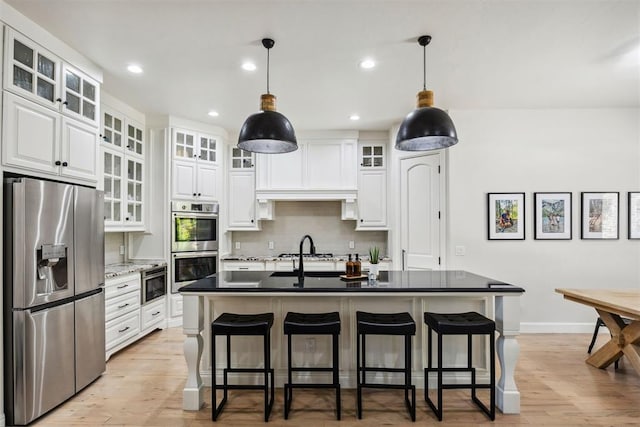 kitchen with a breakfast bar area, stainless steel appliances, and light wood-style floors