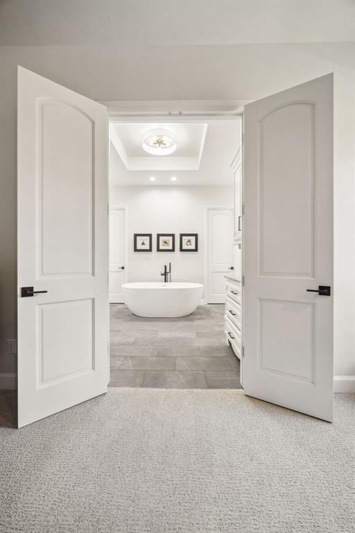 bathroom with baseboards, a freestanding bath, and a tray ceiling
