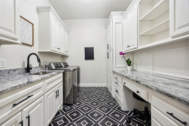 washroom featuring washing machine and dryer, baseboards, dark floors, a sink, and cabinet space