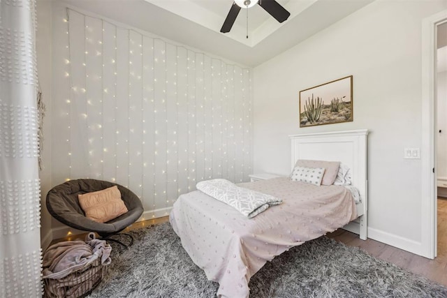 bedroom with a ceiling fan, baseboards, and wood finished floors