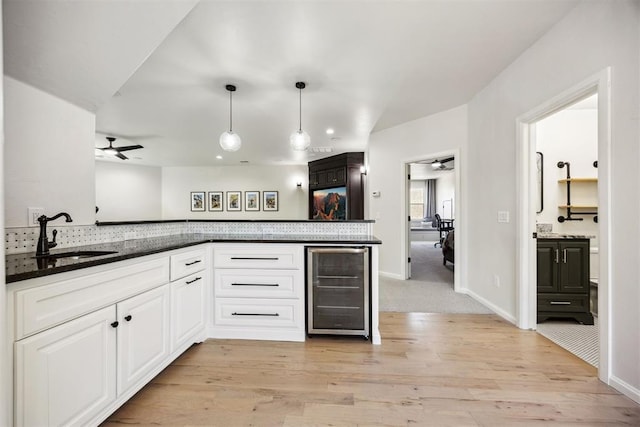 kitchen with ceiling fan, a sink, beverage cooler, white cabinetry, and light wood-type flooring