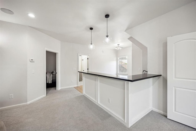 kitchen with hanging light fixtures, dark countertops, baseboards, and light colored carpet