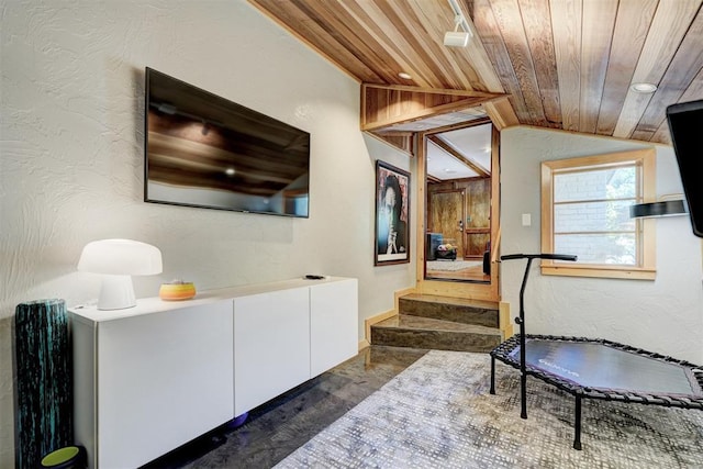 exercise area featuring a textured wall, vaulted ceiling, and wood ceiling