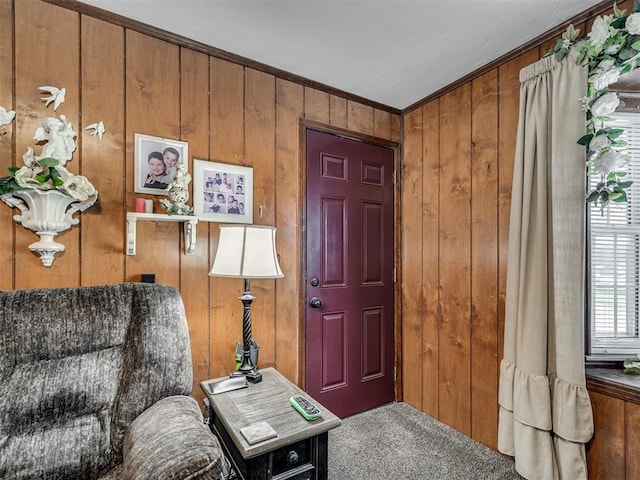 living area with wooden walls, ornamental molding, and carpet