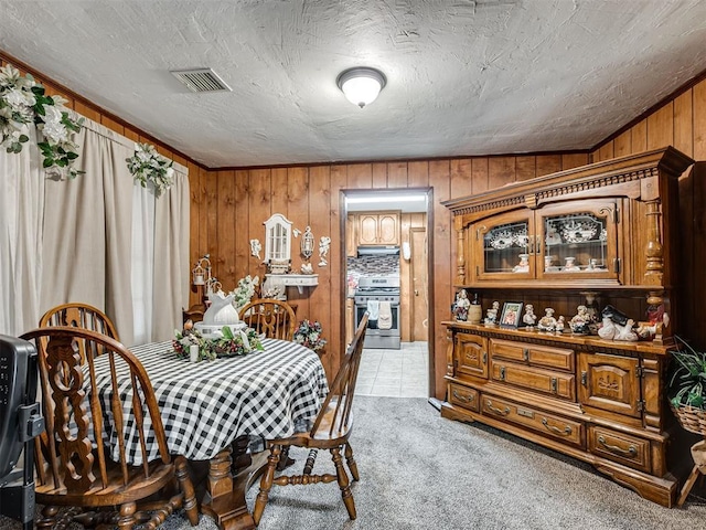 dining room featuring light colored carpet, wood walls, and visible vents