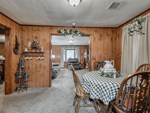 carpeted dining area featuring wooden walls and visible vents