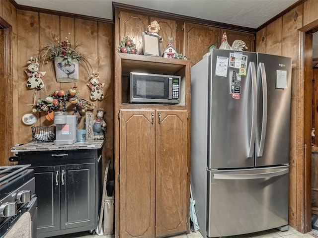 kitchen with light countertops, appliances with stainless steel finishes, brown cabinets, and wooden walls