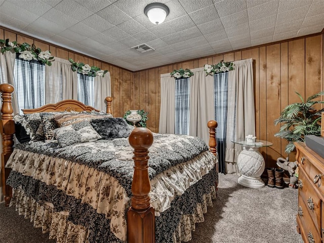 carpeted bedroom with wooden walls and visible vents