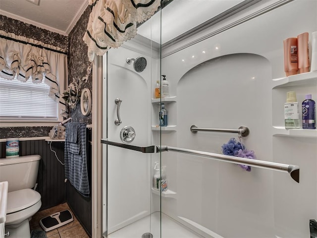 bathroom featuring crown molding, tile patterned flooring, toilet, and a shower stall
