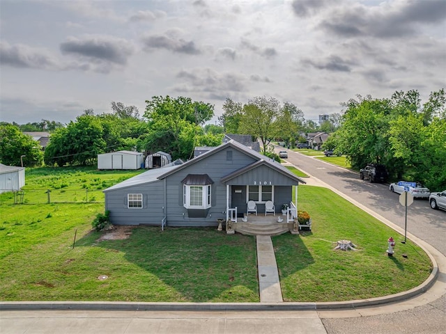 bungalow-style home with fence, covered porch, and a front yard