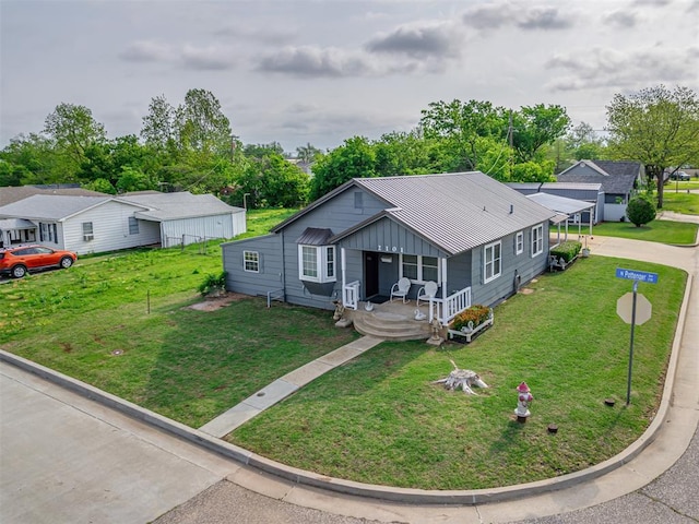bungalow-style house featuring driveway, board and batten siding, covered porch, and a front yard
