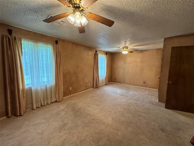 unfurnished room with baseboards, a ceiling fan, a textured ceiling, and light carpet
