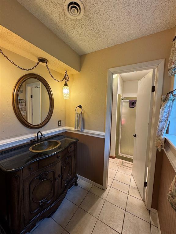 bathroom featuring a textured ceiling, a shower stall, tile patterned flooring, and vanity
