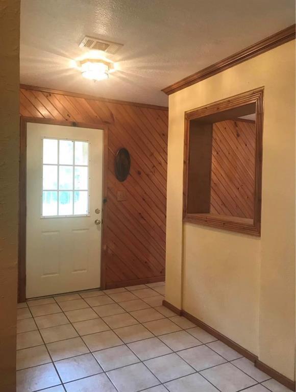 entryway featuring baseboards, ornamental molding, light tile patterned flooring, and visible vents