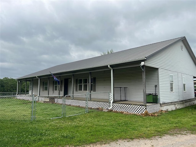 view of front facade featuring fence private yard, covered porch, a front yard, and metal roof