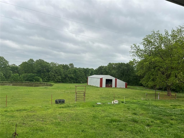 view of yard with a view of trees, fence, an outbuilding, and a garage