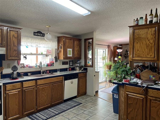 kitchen with light countertops, a textured ceiling, a sink, and dishwasher