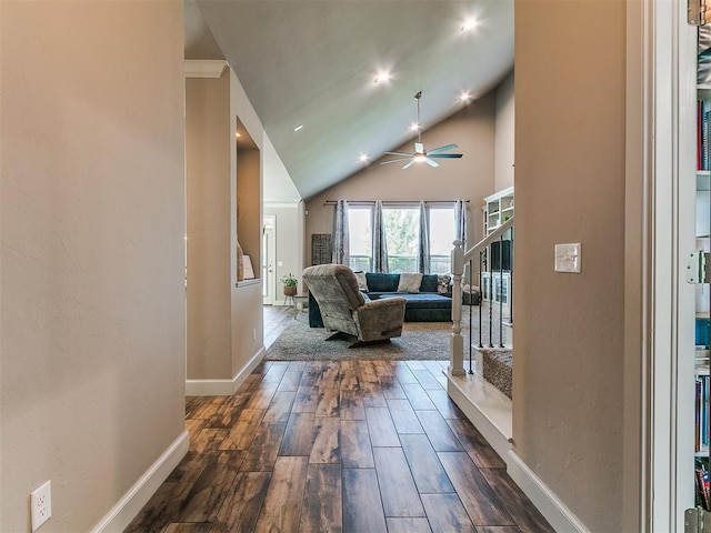 hallway featuring stairway, baseboards, dark wood-style floors, and high vaulted ceiling
