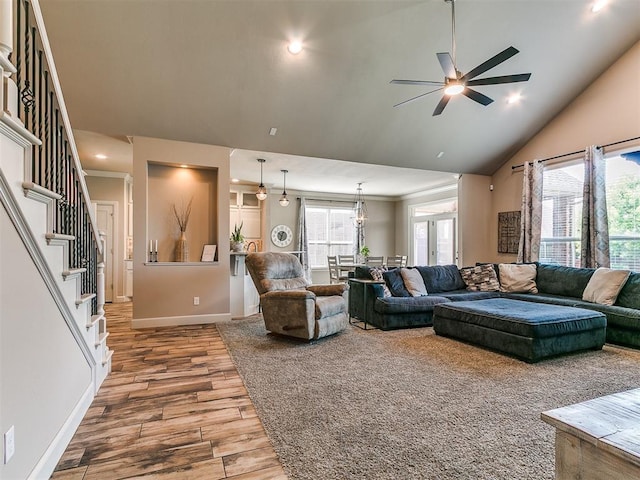 living room with ceiling fan, wood finished floors, baseboards, high vaulted ceiling, and stairs