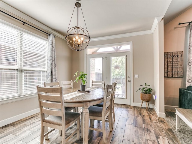 dining area with crown molding, light wood-style flooring, baseboards, and an inviting chandelier