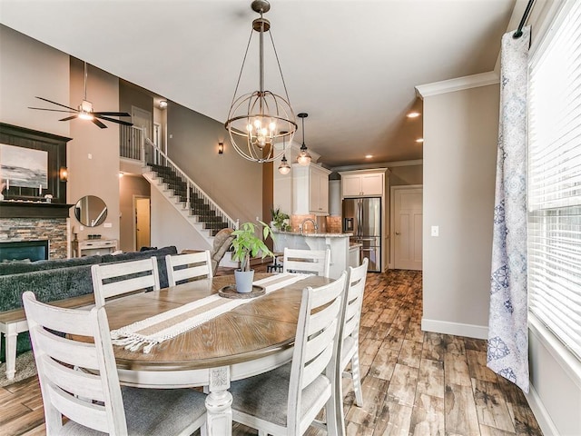 dining space with light wood-style floors, baseboards, a fireplace, and stairs