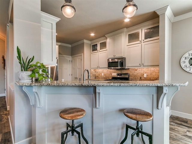 kitchen with baseboards, ornamental molding, appliances with stainless steel finishes, and dark wood-style floors