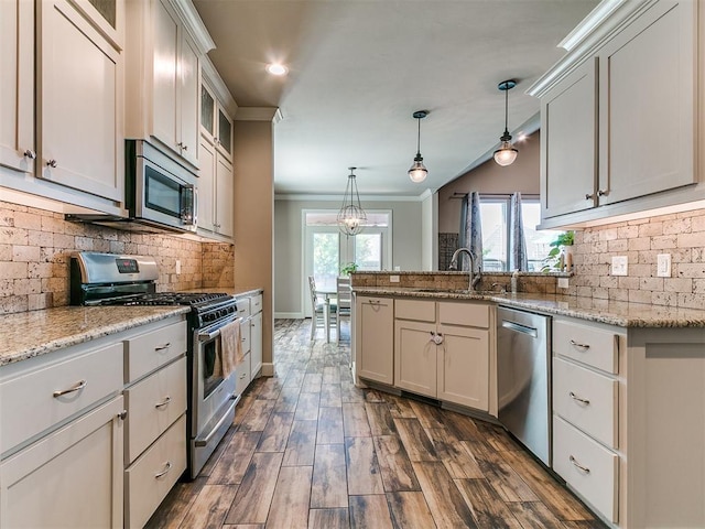 kitchen with backsplash, crown molding, a sink, a peninsula, and stainless steel appliances