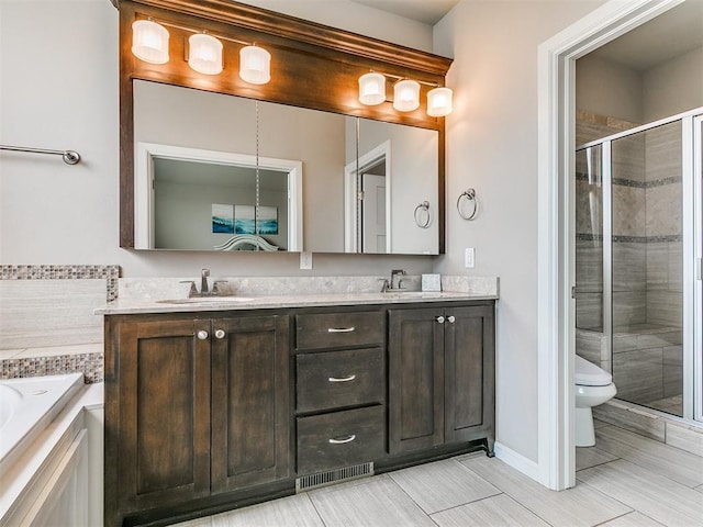 full bathroom featuring a sink, double vanity, toilet, a shower stall, and visible vents